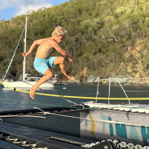 Enfant sautant sur le trampoline du catamaran de François Gabart